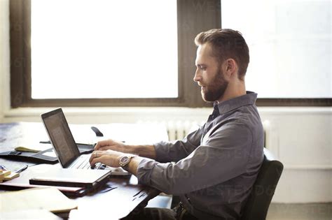 Side View Of Businessman Using Laptop Computer While Working In Office