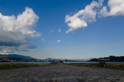 Um Homem Est Parado Em Um Caminho De Concreto Em Frente A Um Lago E O