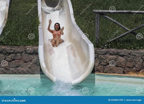 Chica En Bikini Divirtiéndose Cuando Cae Por El Tobogán De Agua En El Parque Acuático Imagen de
