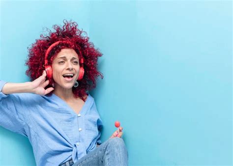 Retrato De Una Joven Latina Sonriente Con El Pelo Afro Rojo De Fondo Azul Sosteniendo Una