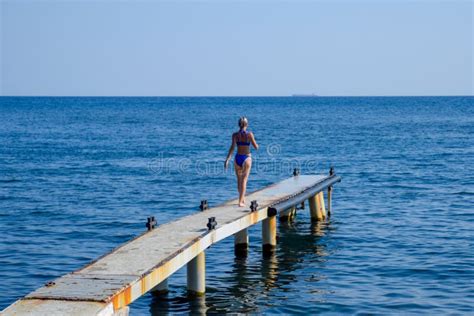 Een Mooi Meisje In Een Blauwe Bikini Loopt De Pijler Aan Het Overzees Mariene Concrete Pijler