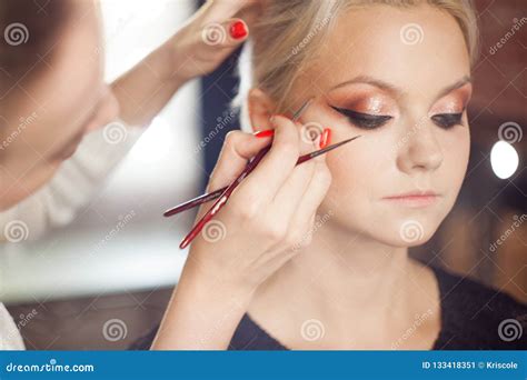 Blonde Joven Hermoso El Artista De Maquillaje Hace Un Maquillaje Elegante Imagen De Archivo