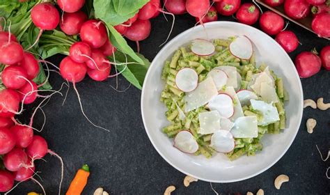 A White Bowl Filled With Food Next To Radishes And Carrots On Top Of A