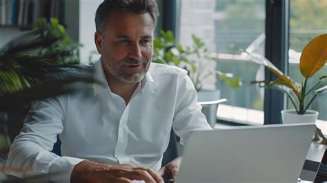 Premium Photo Mature Businessman Contentedly Working On Laptop In Corporate Office