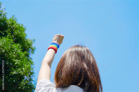 屋外で虹色のリストバンドをした女性の後ろ姿 Photos Adobe Stock