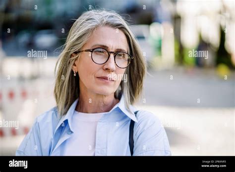 Sad Mature Woman With Silver Hair And Glasses In A European City Portraying Feelings Of