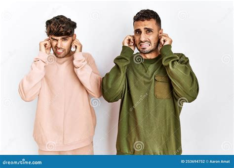 Joven Pareja Gay Parado Sobre Un Aislado Fondo Blanco Cubriendo Las Orejas Con Los Dedos Con