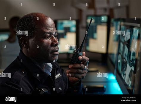 Serious Mature Security Guard In Uniform Looking At Computer Screen