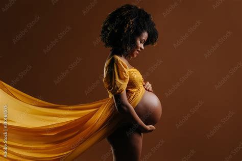 Naked Pregnant Woman In Yellow Dress Touching Belly Stock Photo Adobe Stock