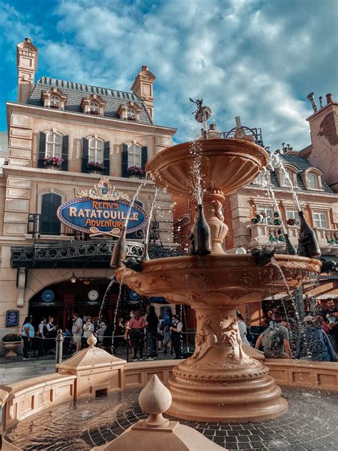 A Fountain In Front Of A Building With People Walking Around It