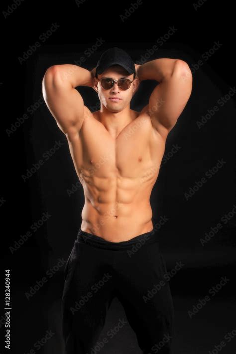 Handsome Bodybuilder Man With A Naked Torso Showing Muscles In Cap And Glasses Stock Photo