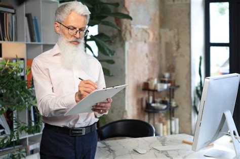 Premium Photo Focused Mature Businessman Working And Taking Notes In His Modern Office