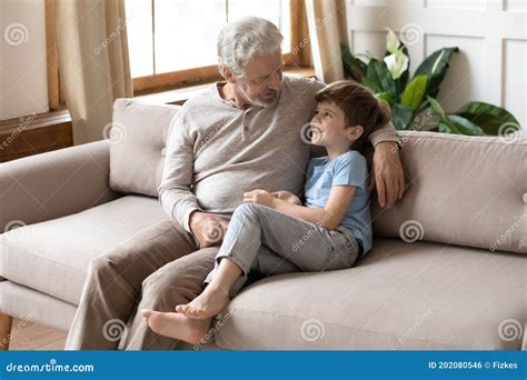 Mature Grandfather Talking With Adorable Grandson Sitting On Couch