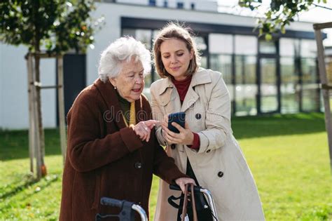 Mature Granddaughter Teaching Grandmother How To Use Smartphone Caregiver Helping Senior Lady