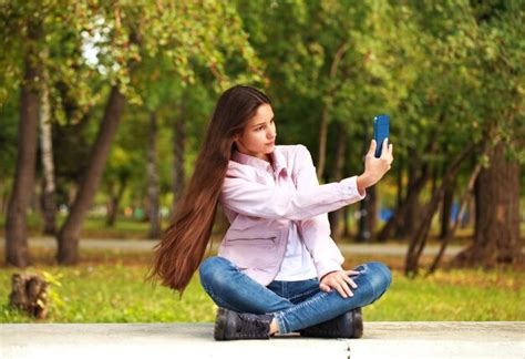 Premium Photo Brunette Girl Photographs Herself On A Cell Phone While Sitting In An Autumn Park