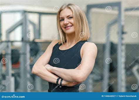 Portrait Of Adult Blonde Fitness Woman Personal Trainer With Folded Hands In Gym Beautiful
