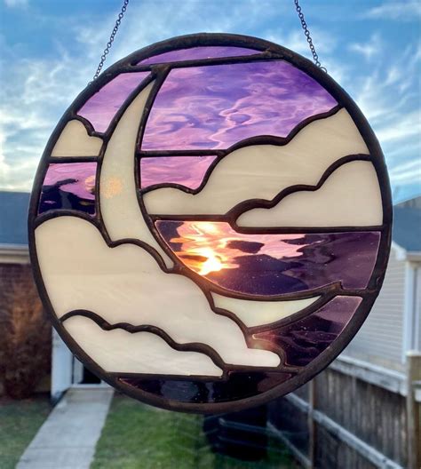 A Stained Glass Sun Catcher Hanging From A Chain On A Houses Front Yard