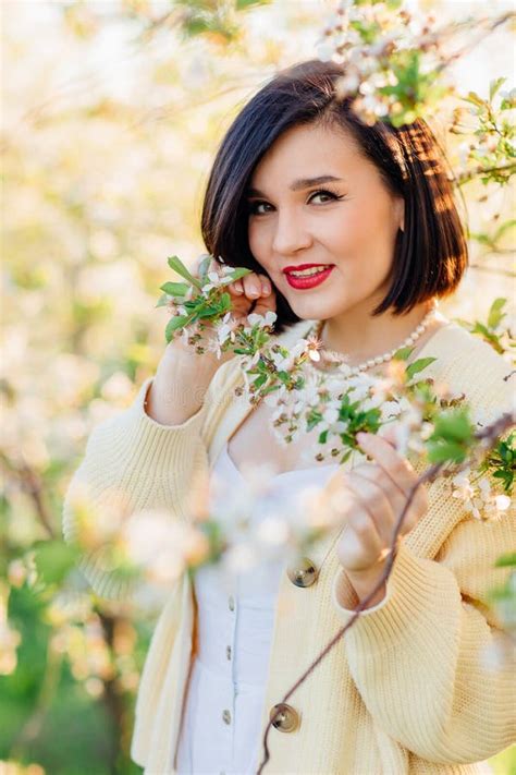 An Attractive Brunette In A White Dress In A Blooming Spring Garden Solar Glare Stock Image