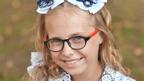 Portrait Of A Smiling Year Old Blonde Girl Pulling A Bow Over Her Head Face Close Up Stock