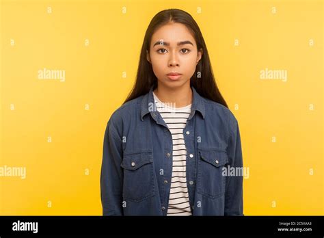 Portrait Of Serious Unsmiling Brunette Girl In Denim Shirt Standing