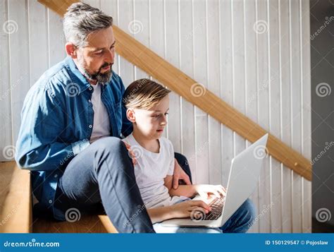 Mature Father With Small Son Sitting On The Stairs Indoors Using Laptop Stock Image Image Of