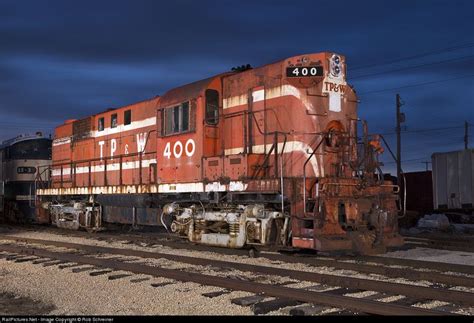 An Old Rusted Train Sitting On The Tracks At Night With Dark Clouds In