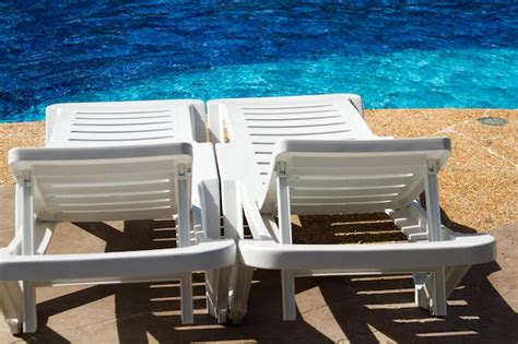 Premium Photo | White plastic pool chairs at the swimming pool.