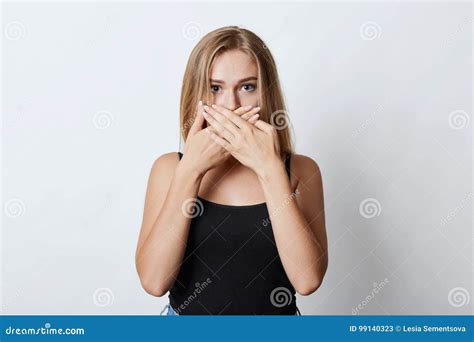 Femme Blonde Avec Les Yeux Brillants Couvrant Sa Bouche De Mains Tout En Essayant De Garder Le