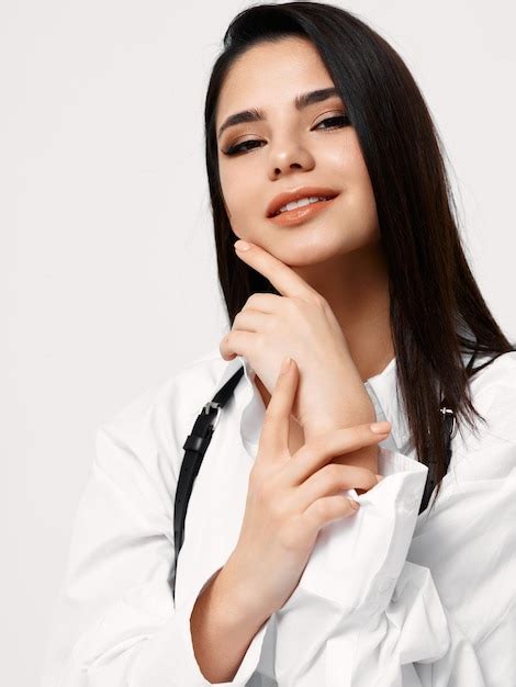 Premium Photo Pretty Brunette In White Shirt With Suspenders Touches Her Face With Her Hand