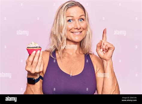 Mittelalter kaukasische blonde Frau trägt Sportkleidung halten cupckae überrascht mit einer Idee