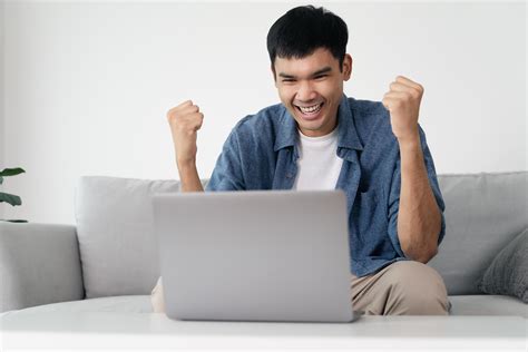 Happy excited Asian man looking at laptop, man receiving good news