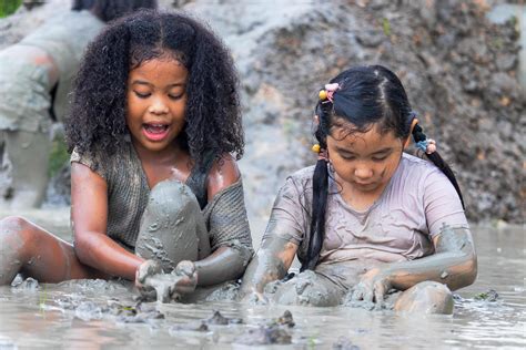 children having fun playing in the mud in the fields on a cloudy day ... 