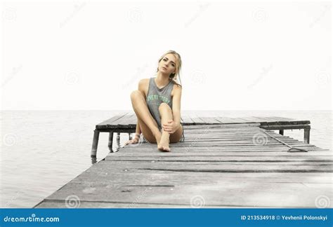 Beautiful Blonde Sits On The Pier Against The Background Of The Sea Stock Photo Image Of Pier