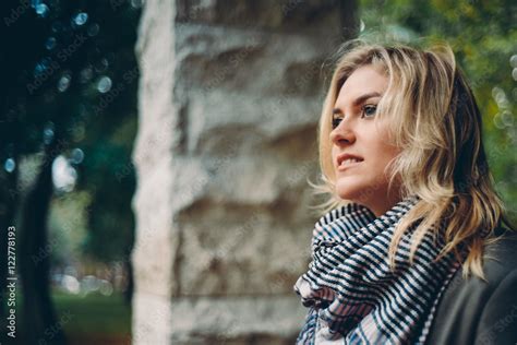 Девушка прячется от дождя под навесом во время прогулки в городском ...