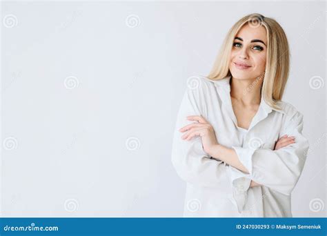 La Blonde Sur Fond Blanc Croise Ses Bras Au Dessus De Sa Poitrine Et Sourit Doucement Image