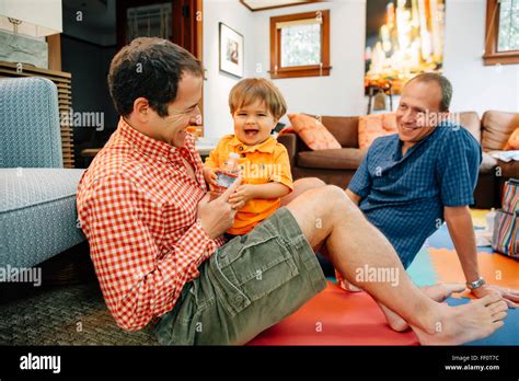Gay Fathers Playing With Baby Son In Living Room Stock Photo Alamy