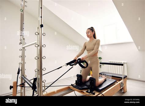 Une Jeune Fille Fait Pilates Sur Un Lit Reformeur Dans Un Studio Lumineux Un Beau Brunette