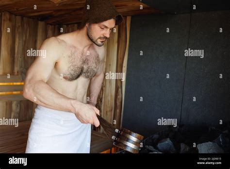 Brutal Man In Sauna Pouring Water From Ladle On Hot Stones Stock Photo Alamy