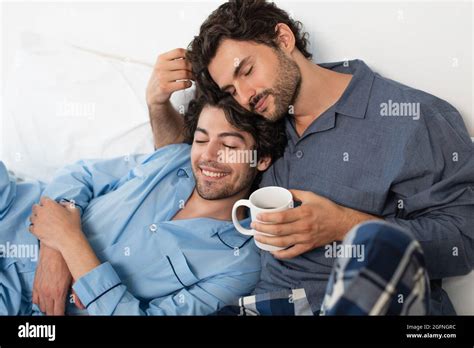 Happy Gay Man Holding Cup Of Tea And Hugging Boyfriend In Bed Stock Photo Alamy