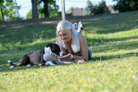 Eine Junge Blonde Frau Liegt Auf Einem Frischgr Nen Rasen Und F Ttert Ihren Hund Mit Gutes