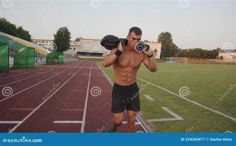 A Muscular Man With A Naked Torso Training In The Stadium And Runs On A