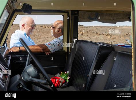 A Senior Gay Couple Shares A Joyful Moment Inside An Off Road Vehicle Engaging In Conversation