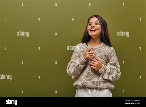 Happy And Trendy Brunette Preteen Girl With Dyed Strands Of Hair Wearing Modern Knitted Sweater