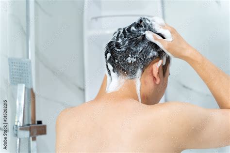 Back View From Below Of Black Haired Naked Man Washing Hair With Shampoo While Talking Shower In
