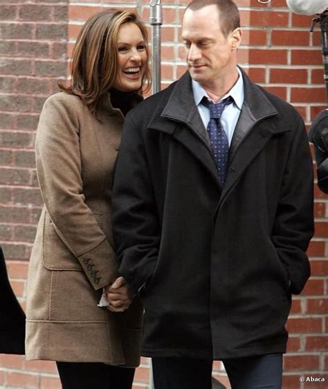 The Man And Woman Are Standing Next To Each Other In Front Of A Brick Wall