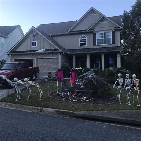 Halloween Decorations In Front Of A House With Skeletons On The Lawn