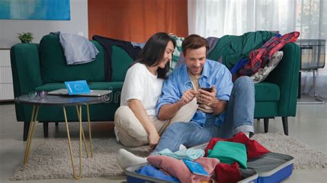 Diverse Gay Couple Sit On Floor And Book Tickets Online On Smartphone
