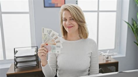 Blonde Woman In Office Holding Czech Currency With Cheerful Expression Stock Photo Image Of