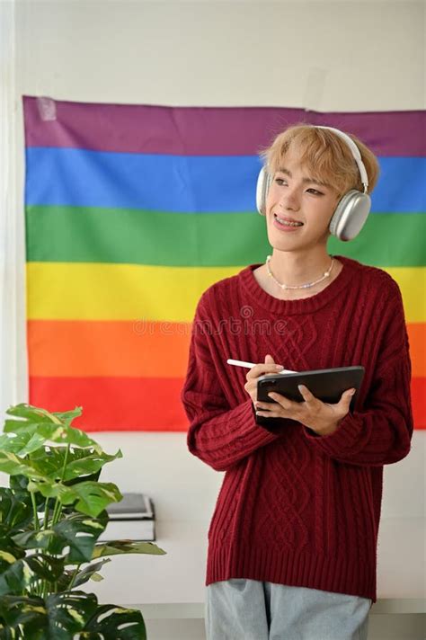 A Happy Asian Gay Man Is Listening To Music While Standing In His Room