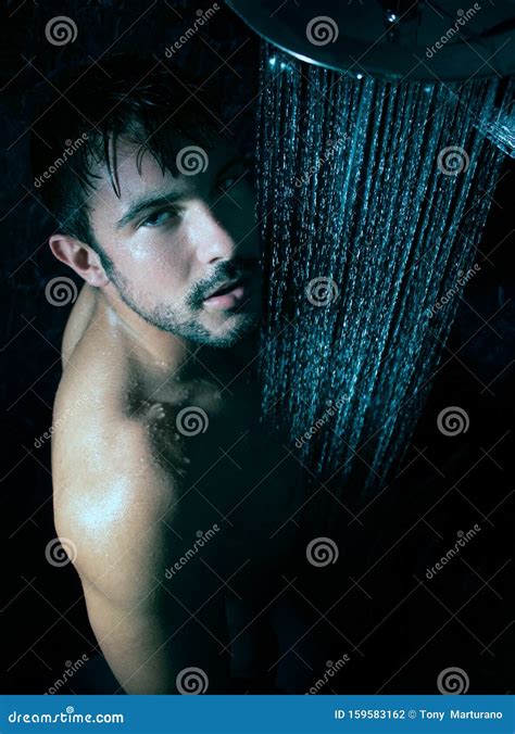 Portrait Of Handsome Naked Man With Beard And Blue Eyes Under A Rainfall Shower Looking At